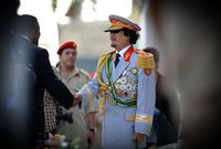 القذافي في بدلة عسكرية رسمية ذات لون غير تقليدي بها عدد كبير من النياشين والأوسمة العسكرية