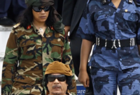 القذافي مرتديًا زيه الغير تقليدي واضعًا عليه كذلك خريطة قارة أفريقيا
